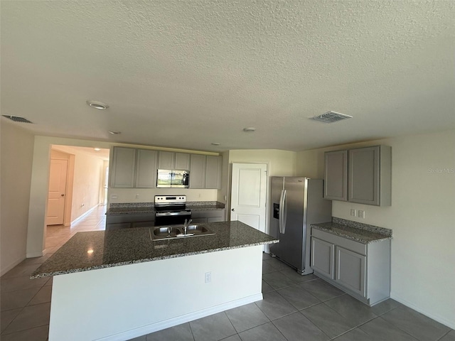 kitchen with a center island with sink, visible vents, appliances with stainless steel finishes, gray cabinetry, and a sink