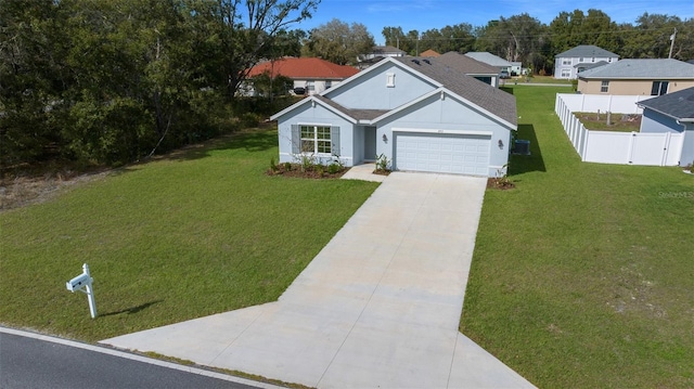 view of front of home with stucco siding, fence, a garage, driveway, and a front lawn