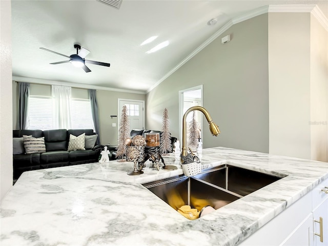 interior space with light stone counters, crown molding, white cabinets, vaulted ceiling, and a sink