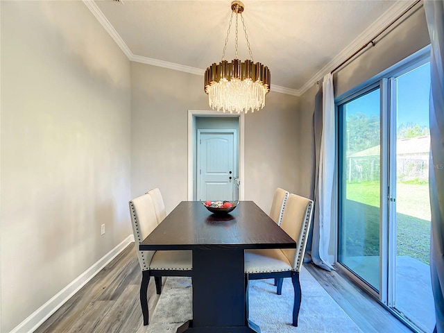 dining area featuring ornamental molding, a notable chandelier, baseboards, and wood finished floors