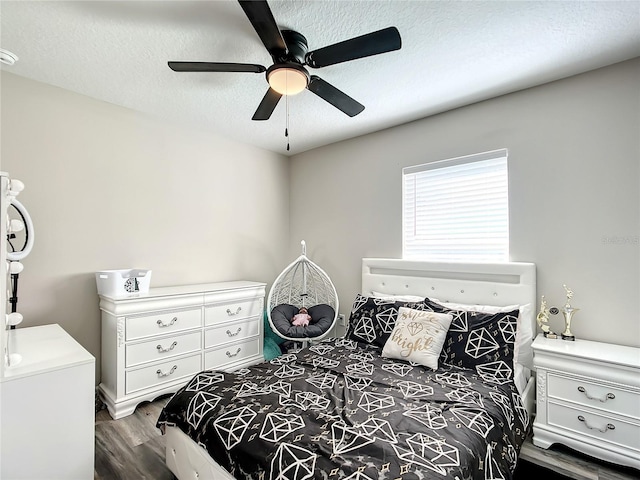 bedroom with a textured ceiling, dark wood-type flooring, and a ceiling fan