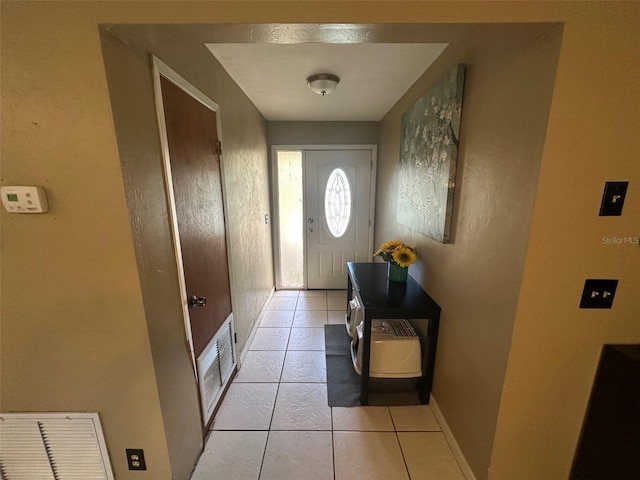 doorway with light tile patterned floors, visible vents, and baseboards