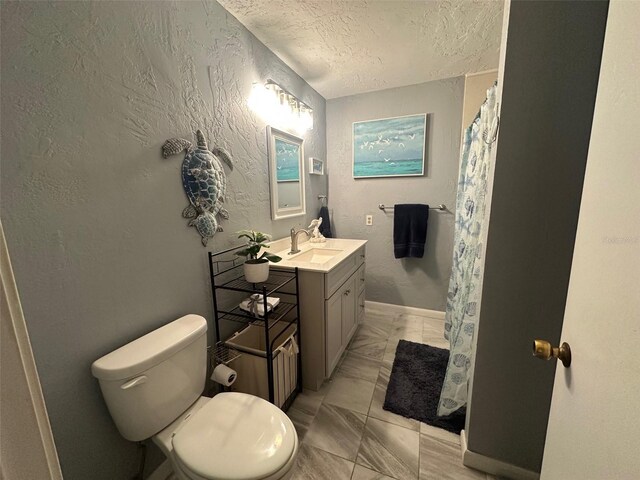 bathroom with a textured wall, toilet, marble finish floor, a textured ceiling, and vanity