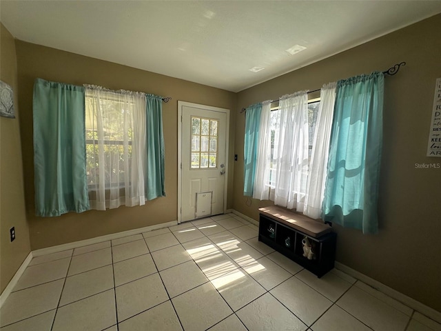 doorway featuring light tile patterned floors and baseboards