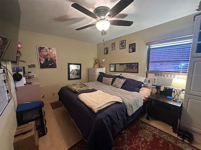 bedroom with a ceiling fan, baseboards, cooling unit, and wood finished floors