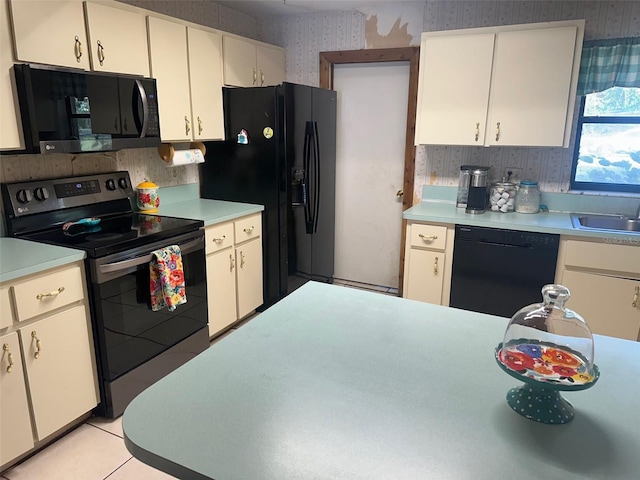 kitchen featuring wallpapered walls, light tile patterned floors, light countertops, black appliances, and a sink