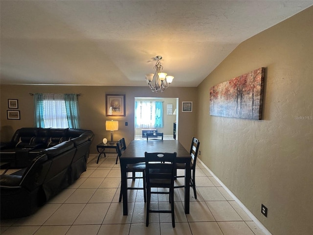 dining space with lofted ceiling, a textured wall, light tile patterned flooring, baseboards, and an inviting chandelier