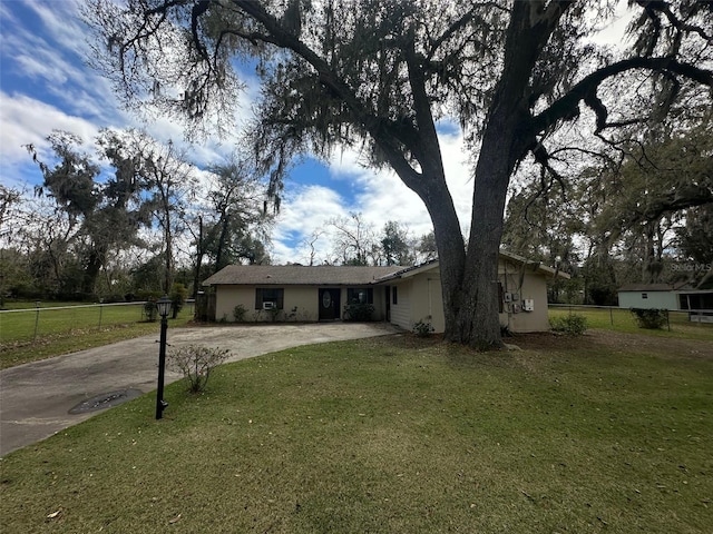 view of front facade with driveway, a front lawn, fence, and stucco siding