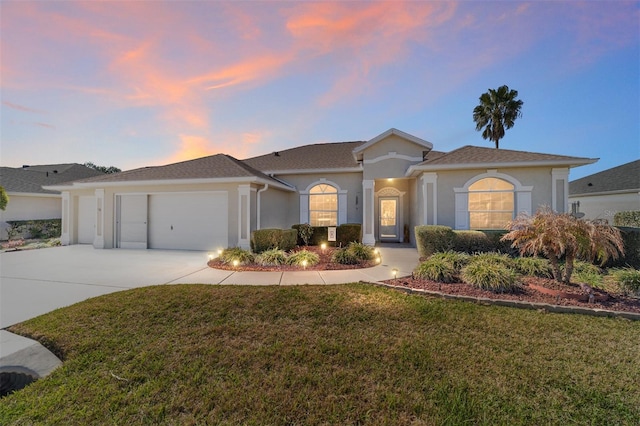 ranch-style home featuring driveway, a yard, an attached garage, and stucco siding