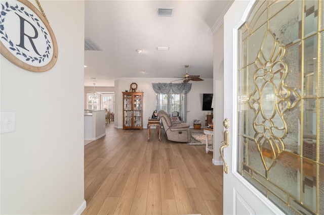 interior space featuring light wood-type flooring, visible vents, crown molding, and baseboards