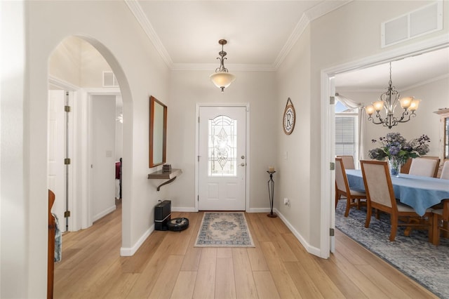 entrance foyer with ornamental molding, light wood-type flooring, visible vents, and arched walkways