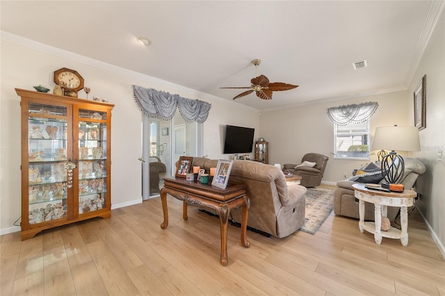 living room featuring ornamental molding, visible vents, light wood-style flooring, and a ceiling fan