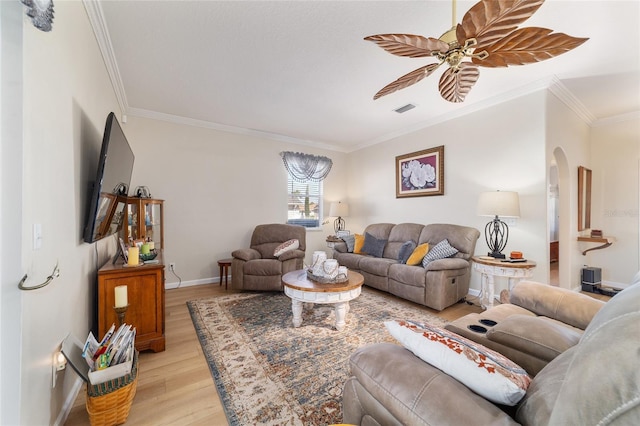 living area featuring a ceiling fan, visible vents, baseboards, ornamental molding, and light wood finished floors