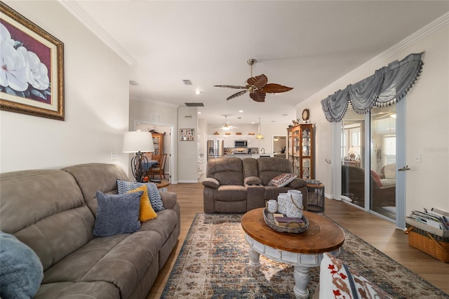 living room featuring visible vents, crown molding, baseboards, and wood finished floors