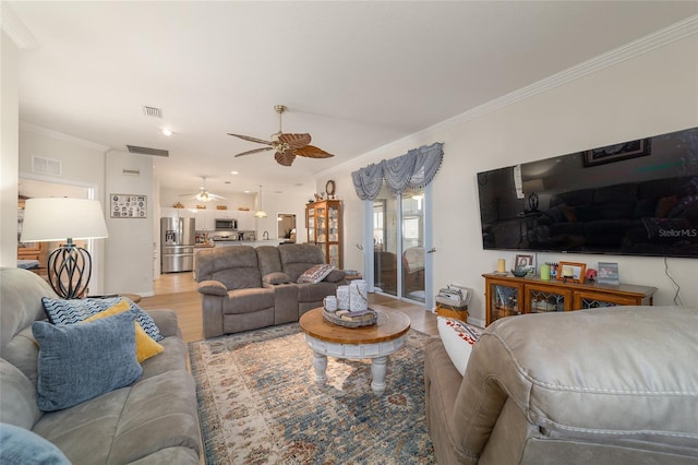 living room with ceiling fan, visible vents, wood finished floors, and ornamental molding