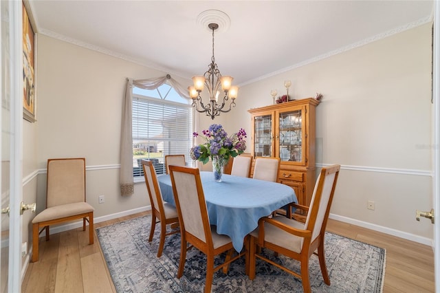 dining area with a chandelier, crown molding, light wood-style flooring, and baseboards