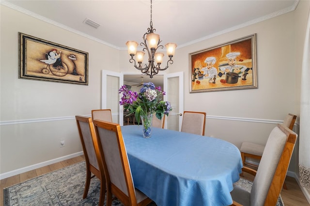 dining room featuring baseboards, crown molding, visible vents, and wood finished floors