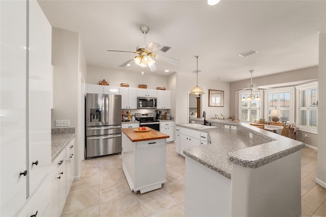 kitchen featuring visible vents, wooden counters, appliances with stainless steel finishes, a sink, and a peninsula