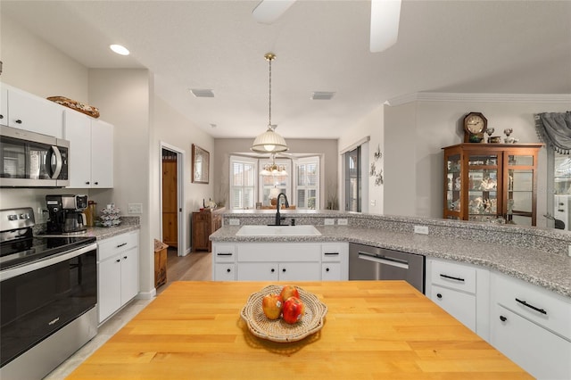 kitchen featuring hanging light fixtures, appliances with stainless steel finishes, a sink, and visible vents