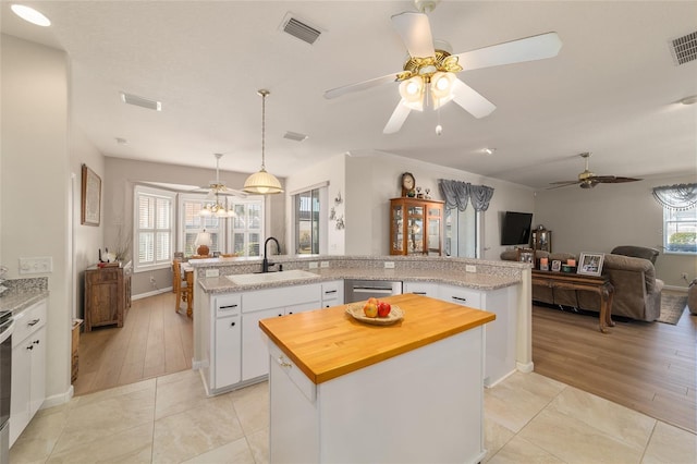 kitchen with butcher block counters, a sink, visible vents, open floor plan, and an island with sink