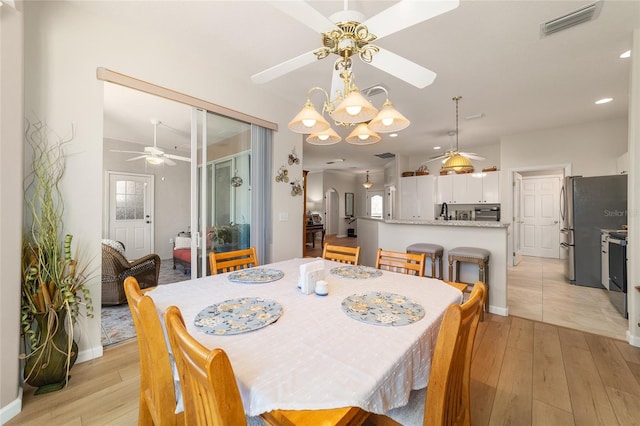 dining area with a ceiling fan, light wood-type flooring, visible vents, and baseboards