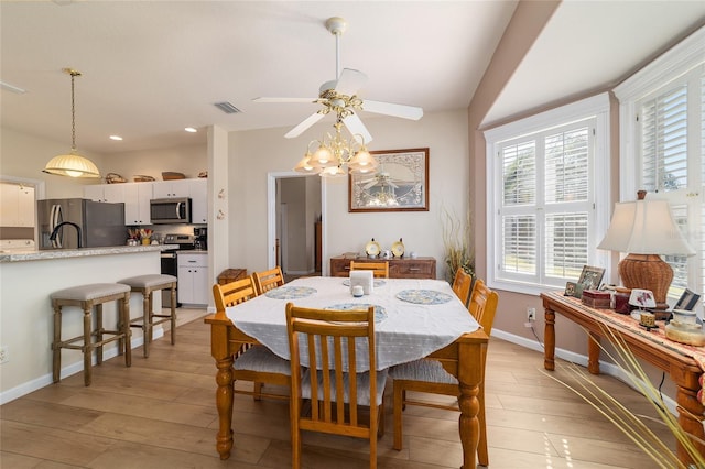 dining room with lofted ceiling, ceiling fan, visible vents, baseboards, and light wood finished floors