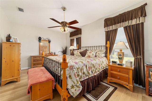 bedroom featuring ceiling fan, multiple windows, visible vents, and wood finished floors