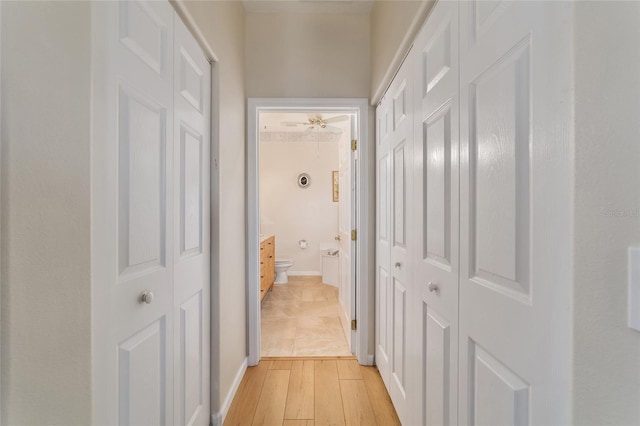 hallway featuring light wood finished floors and baseboards