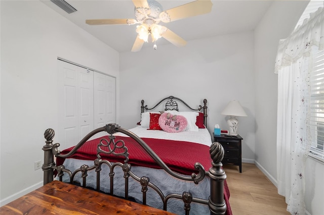 bedroom with a closet, visible vents, a ceiling fan, light wood-type flooring, and baseboards