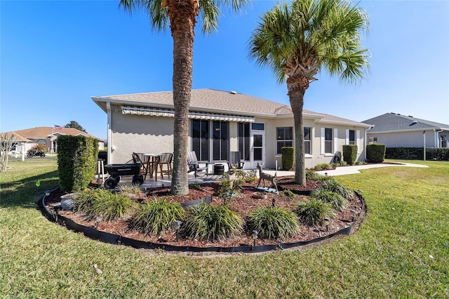 rear view of property featuring a yard, a patio area, and stucco siding