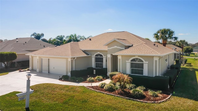 mediterranean / spanish house featuring a garage, a shingled roof, concrete driveway, stucco siding, and a front lawn