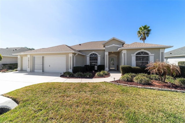 view of front of house with concrete driveway, a front lawn, an attached garage, and stucco siding