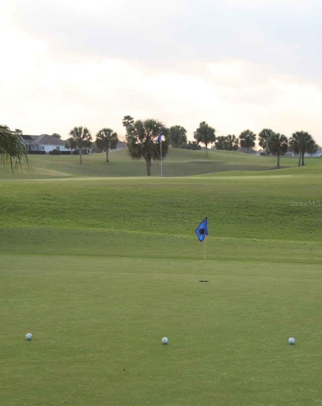 surrounding community with view of golf course and a lawn