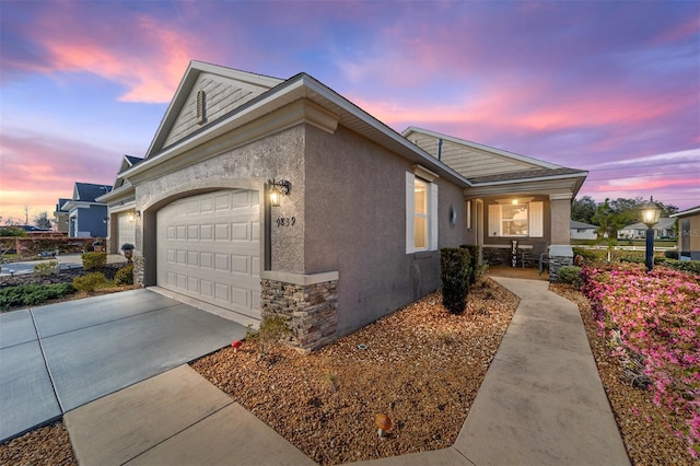 view of home's exterior featuring a garage, stone siding, concrete driveway, and stucco siding