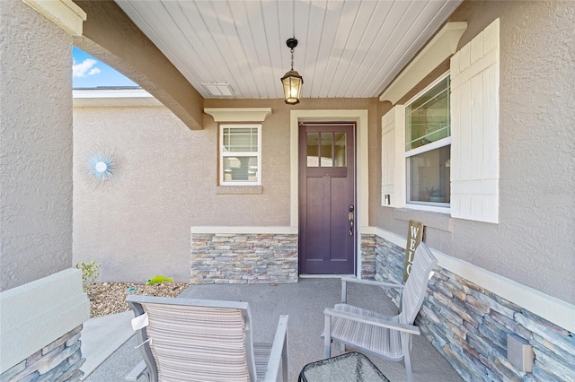 doorway to property featuring stone siding and stucco siding