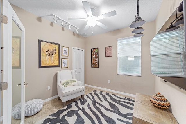 sitting room featuring a textured ceiling, track lighting, and baseboards