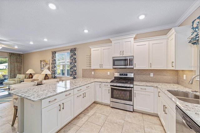 kitchen featuring white cabinets, stainless steel appliances, a sink, and open floor plan