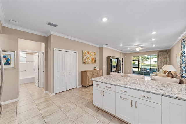 kitchen with light stone countertops, open floor plan, visible vents, and white cabinets