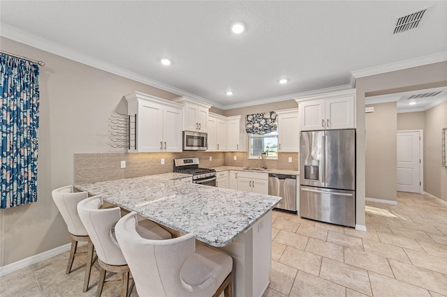 kitchen with a breakfast bar area, a peninsula, visible vents, white cabinetry, and appliances with stainless steel finishes