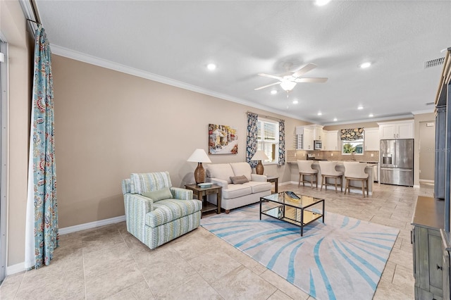 living area with baseboards, visible vents, ceiling fan, and crown molding