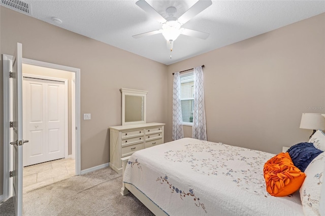 bedroom featuring light colored carpet, visible vents, a ceiling fan, a textured ceiling, and baseboards