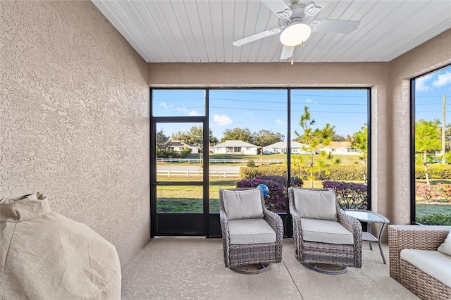 sunroom / solarium with ceiling fan and a residential view