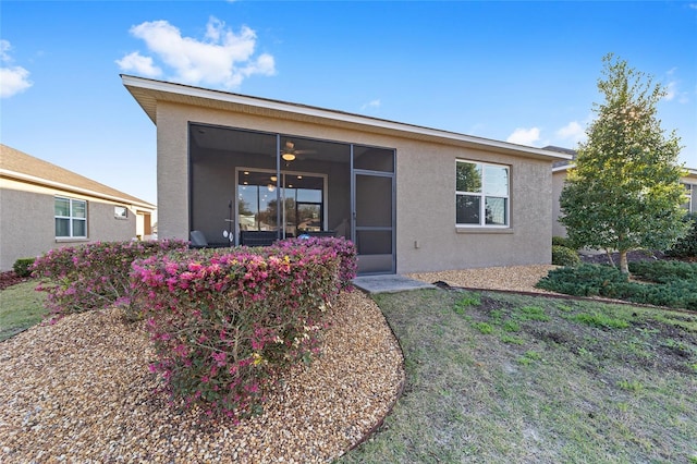 rear view of property featuring ceiling fan and stucco siding