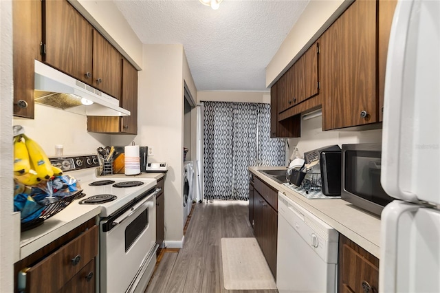 kitchen with white appliances, dark wood-type flooring, light countertops, a textured ceiling, and under cabinet range hood