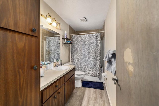 bathroom featuring toilet, wood finished floors, shower / bath combo with shower curtain, a textured ceiling, and vanity