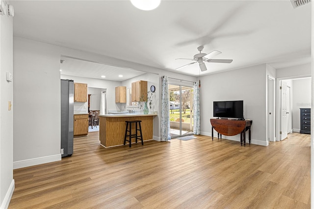 living room with light wood-style floors, visible vents, ceiling fan, and baseboards