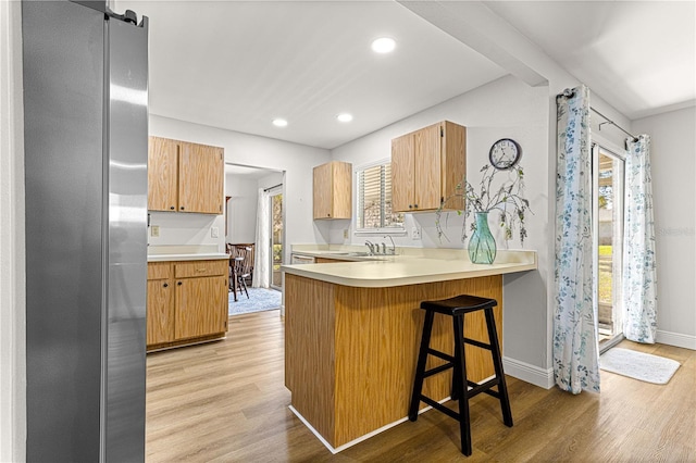 kitchen with a barn door, a peninsula, light countertops, light wood-type flooring, and freestanding refrigerator