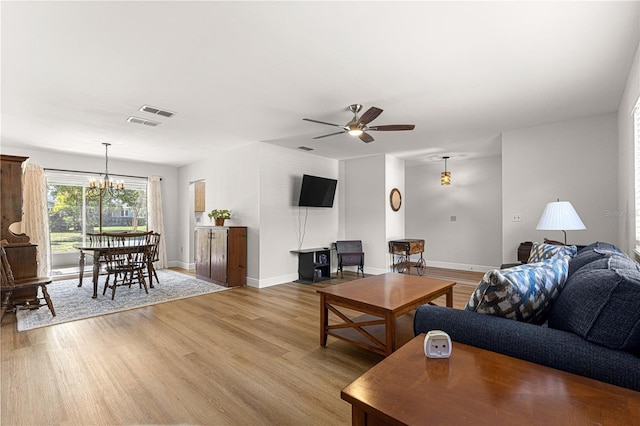 living room with light wood-style floors, visible vents, baseboards, and ceiling fan with notable chandelier