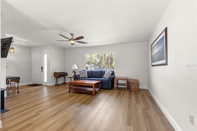 living area with light wood-type flooring, ceiling fan, and baseboards