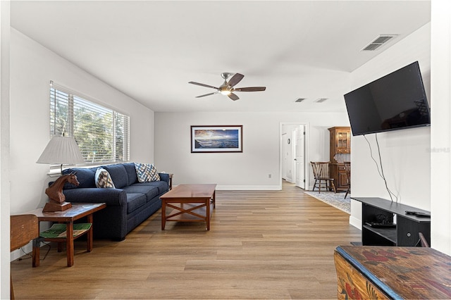 living room with a ceiling fan, baseboards, visible vents, and light wood finished floors